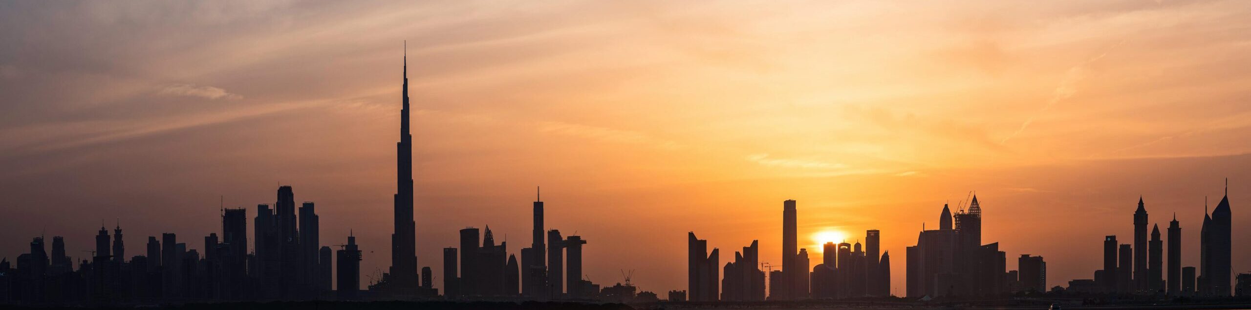 Enchanting view of Dubai's skyscrapers at sunset with the iconic Burj Khalifa outlined against the vivid sky.